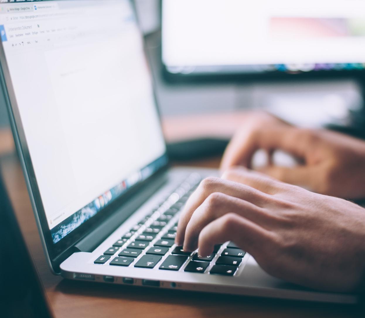 Mains d'une personne tapant sur un clavier d'ordinateur portable